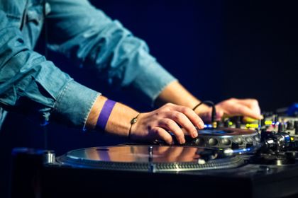 Hands on a turntable and mixer against a navy background
