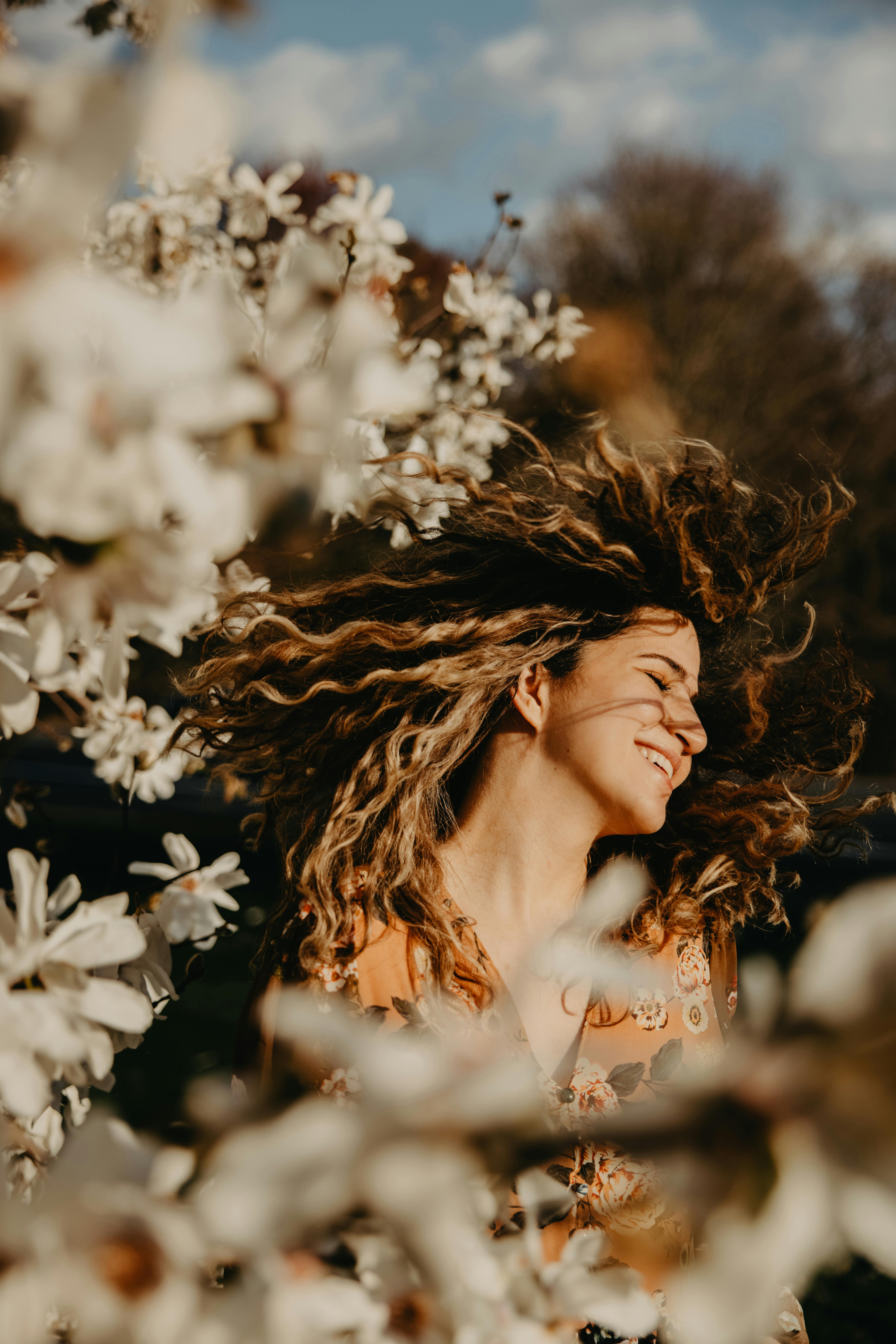 happy woman with curly hair near flowers