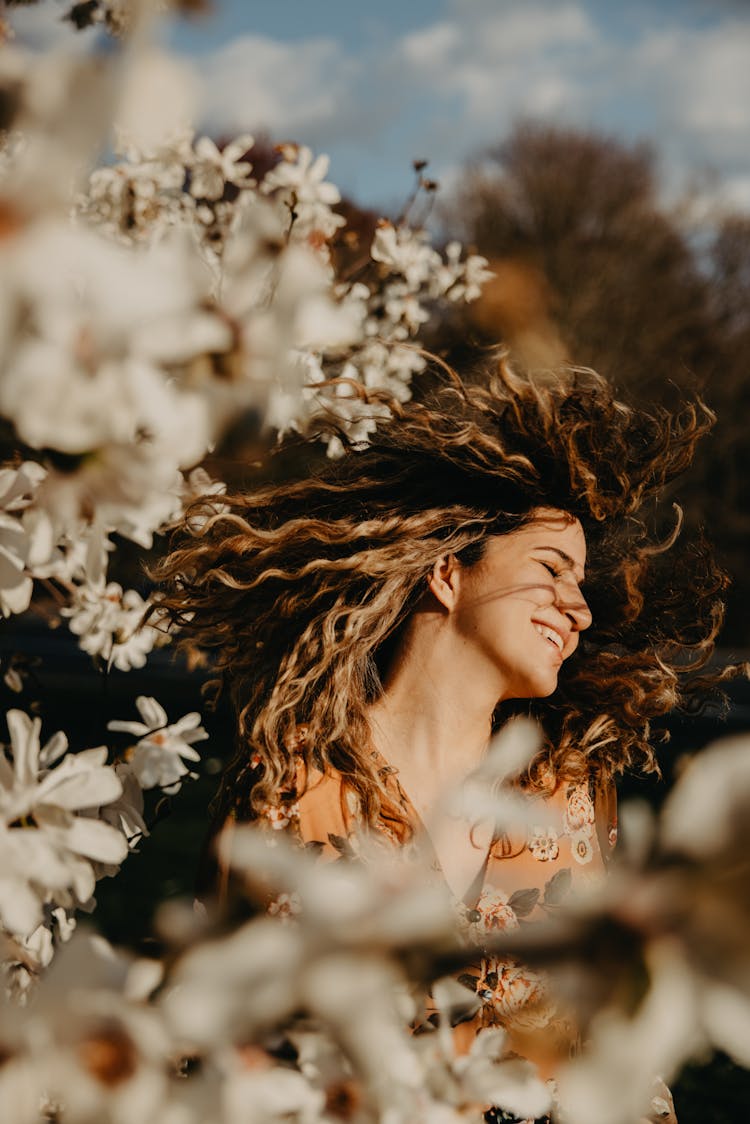 Happy Woman With Curly Hair Near Flowers