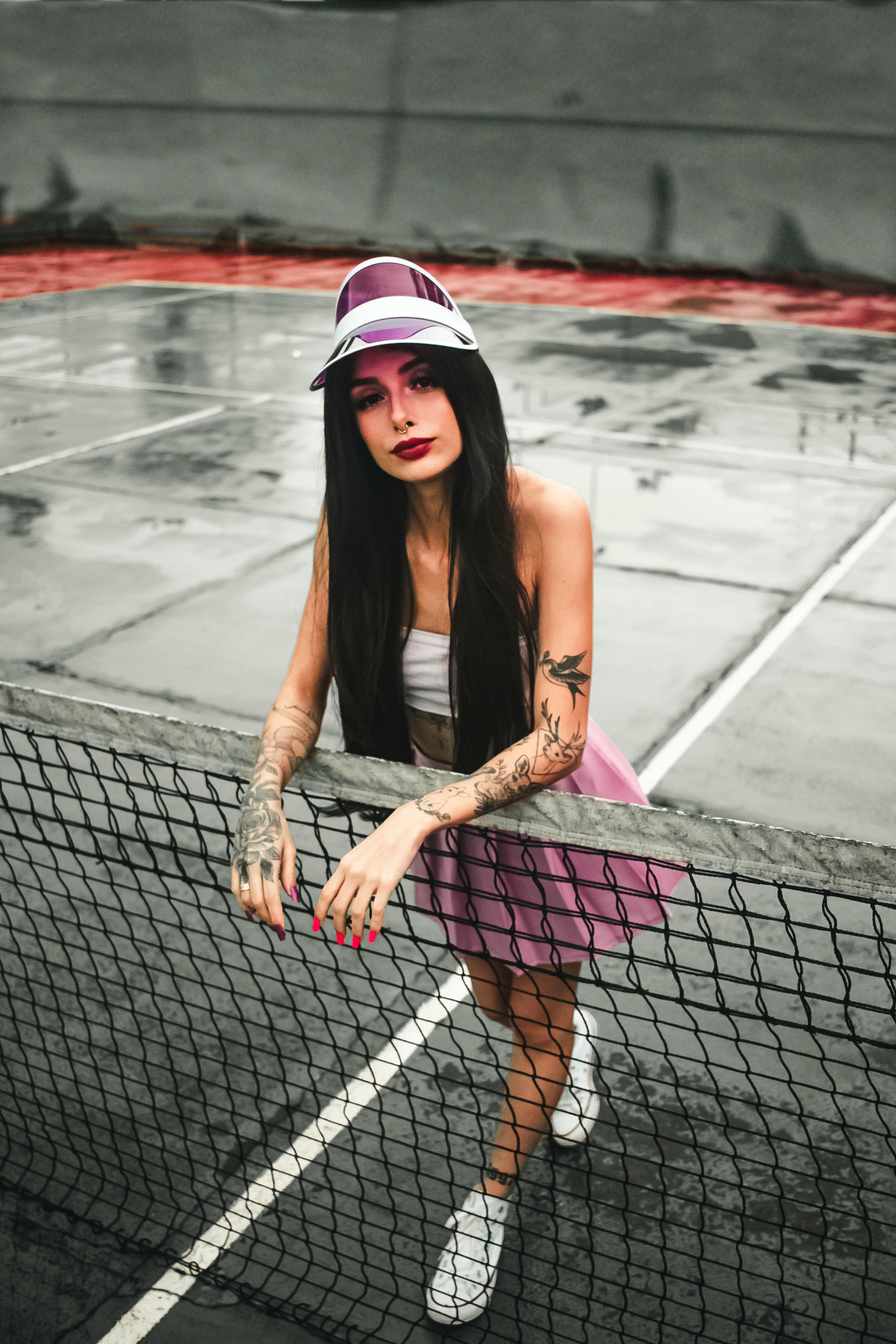 sportswoman with tattoos behind fence on tennis court