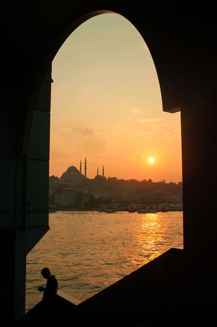 Aged arched construction located on waterfront near rippling sea against shore with historic buildings in coastal city at sundown time