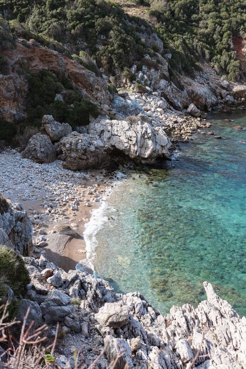 Free From above of shore between dry mounts with lush trees against wavy ocean in sunlight Stock Photo
