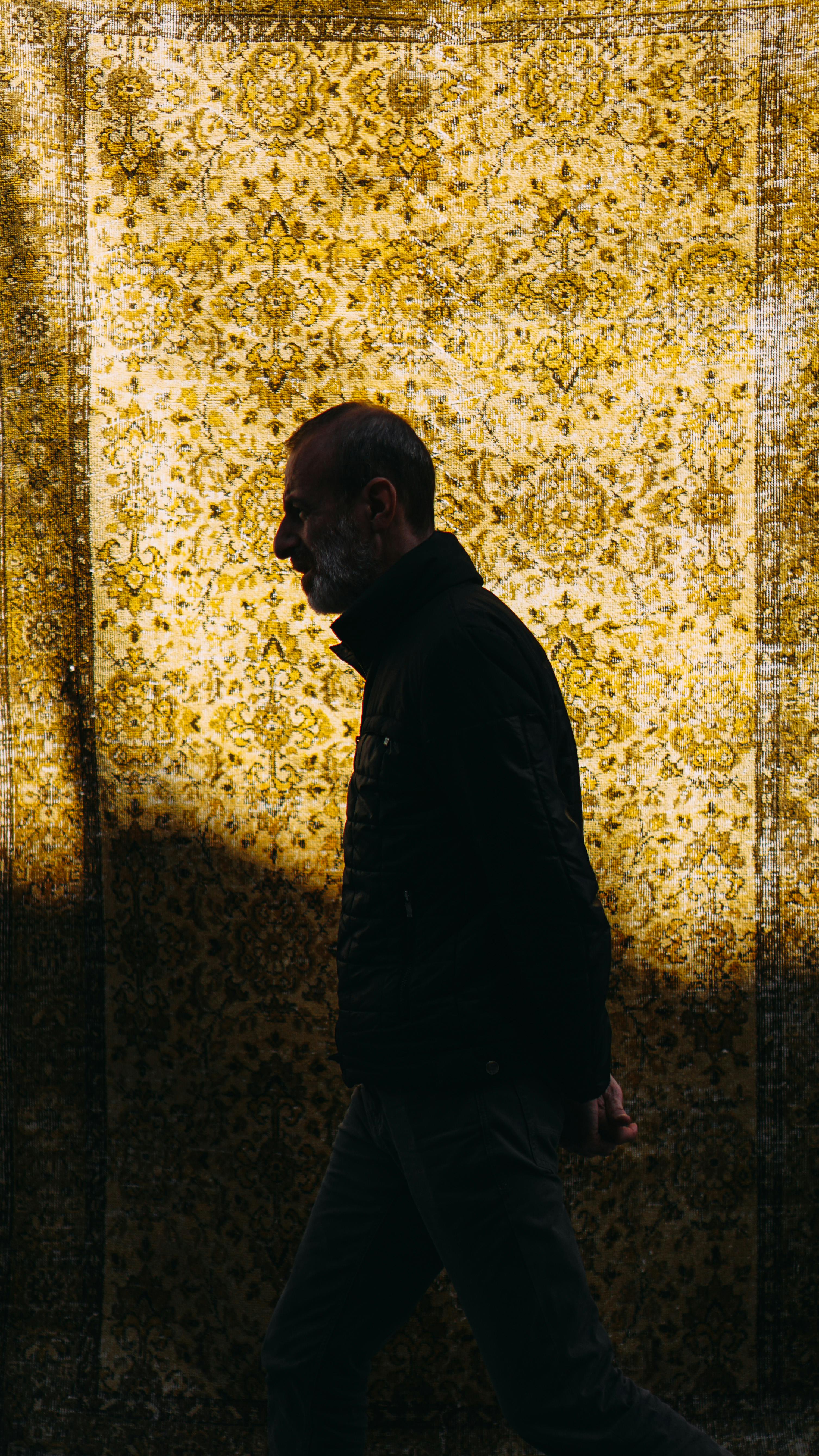 middle aged man walking against carpet with ornament at dusk