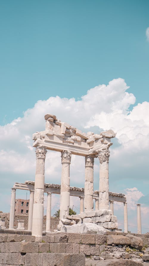 Old stone temple with colonnade and decor under blue sky with cumulus clouds in Side Turkey