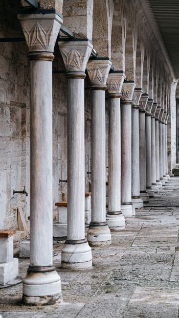 Colonnade at entrance of shabby medieval Muslim mosque with columns faucets and seat for parishioners