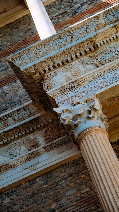 From below of aged stone construction with old decorated columns with ornamental elements and inscription