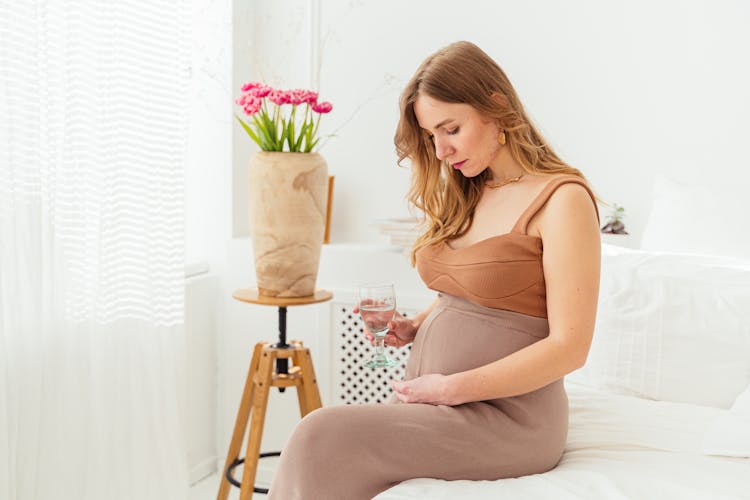 A Pregnant Woman Staring At Her Baby Bump