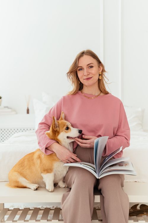 Free A relaxed woman with a corgi dog enjoys reading at home, capturing domestic tranquility. Stock Photo