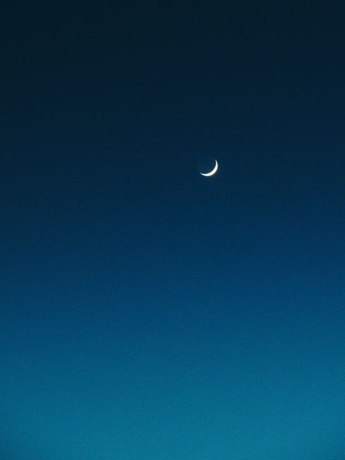 A serene crescent moon against a clear blue night sky, perfect for backgrounds.