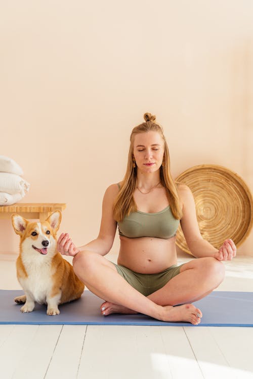 Pregnant Woman Doing Yoga Pose Beside Her Dog