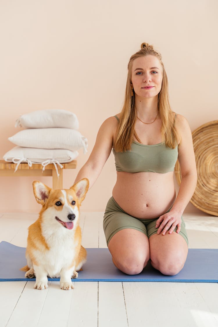 Pregnant Woman And Dog Sitting On Fitness Mat