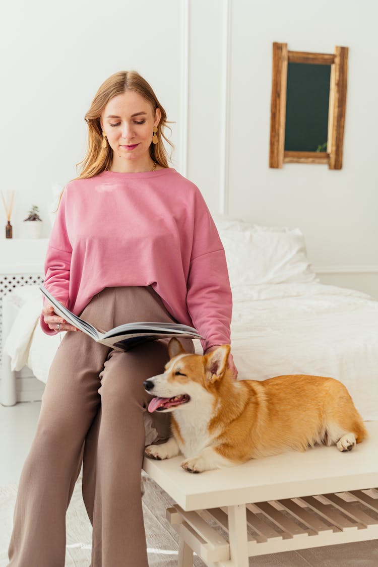 A Woman Reading A Magazine Beside Her Dog 