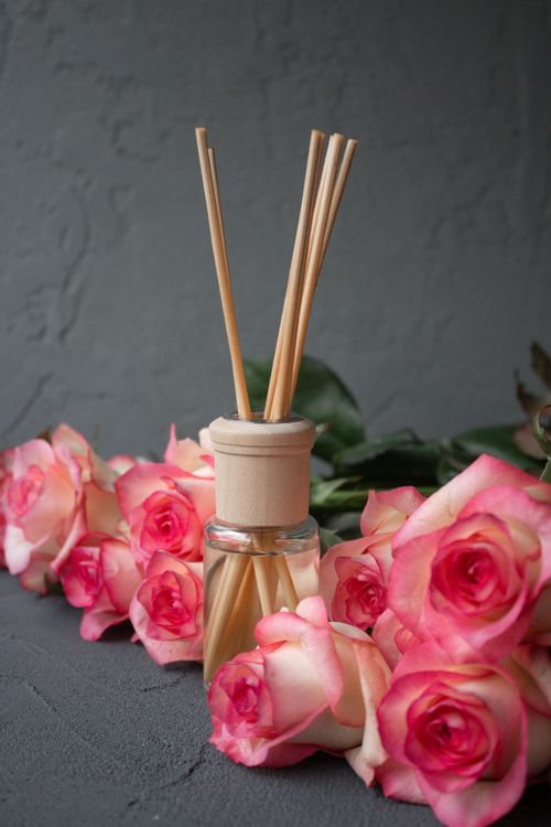 Free Aromatic reed diffuser and vibrant roses create a serene ambiance. Stock Photo