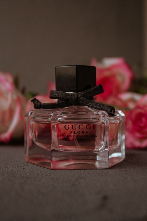 Free Minimalist transparent bottle of perfume placed on table with bunch of pink flowers against brown background Stock Photo