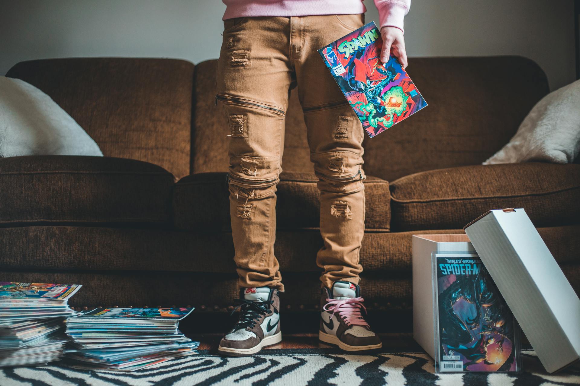 Crop unrecognizable person with collection of comic books in room