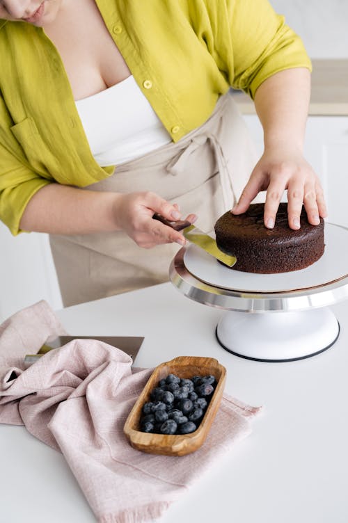 Crop cook preparing chocolate cake with berries