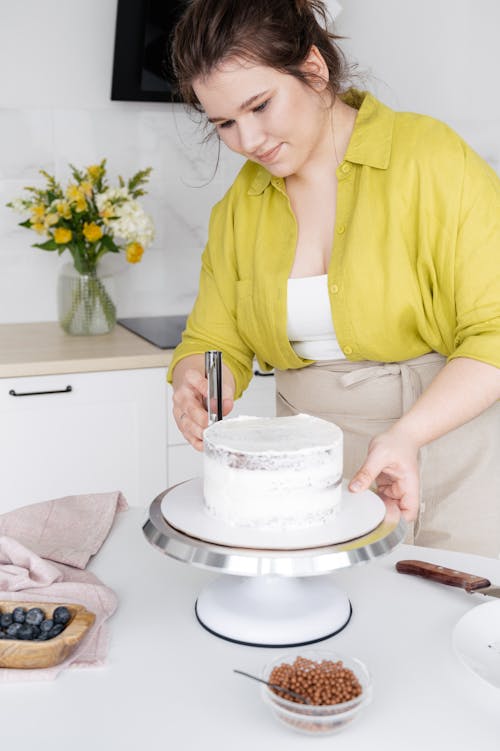 Woman preparing delicious cake in kitchen