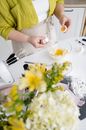 Crop woman breaking egg into bowl in house kitchen
