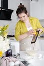 Young focused female adding aromatic lemon zest to cake dough in bowl on table in house