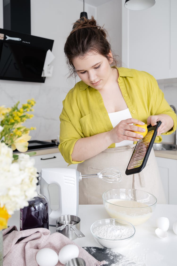 Attentive Woman Grating Lemon Zest While Cooking In Kitchen