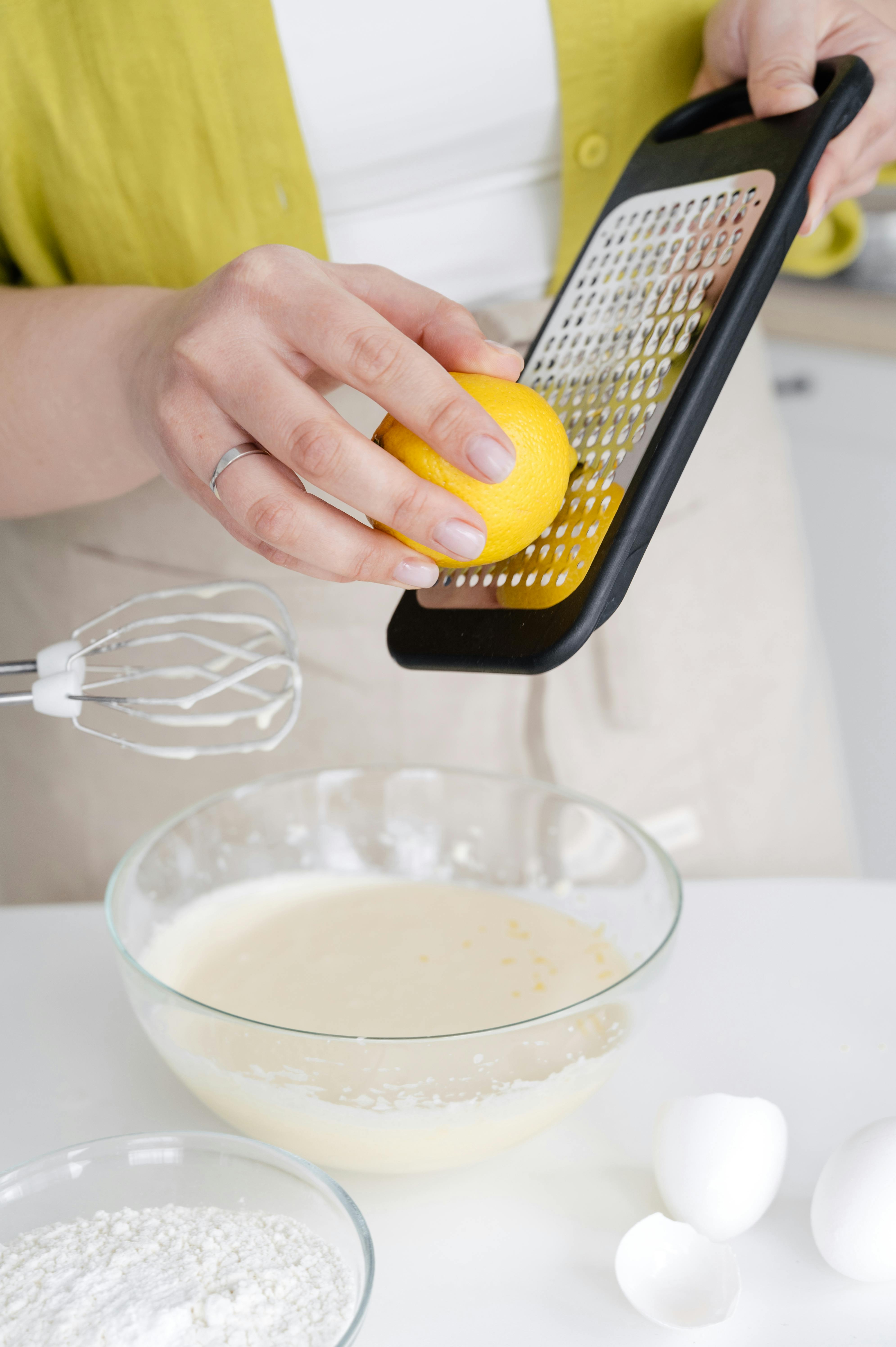 crop woman grating lemon zest while cooking in kitchen