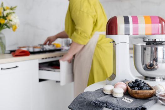 A vibrant kitchen featuring a colorful mixer, blueberries, and French macarons on a counter.