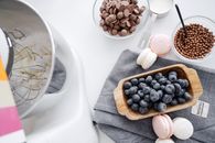 From above composition planetary mixer macaroons wooden bowl with blueberry and chocolate disks for melting