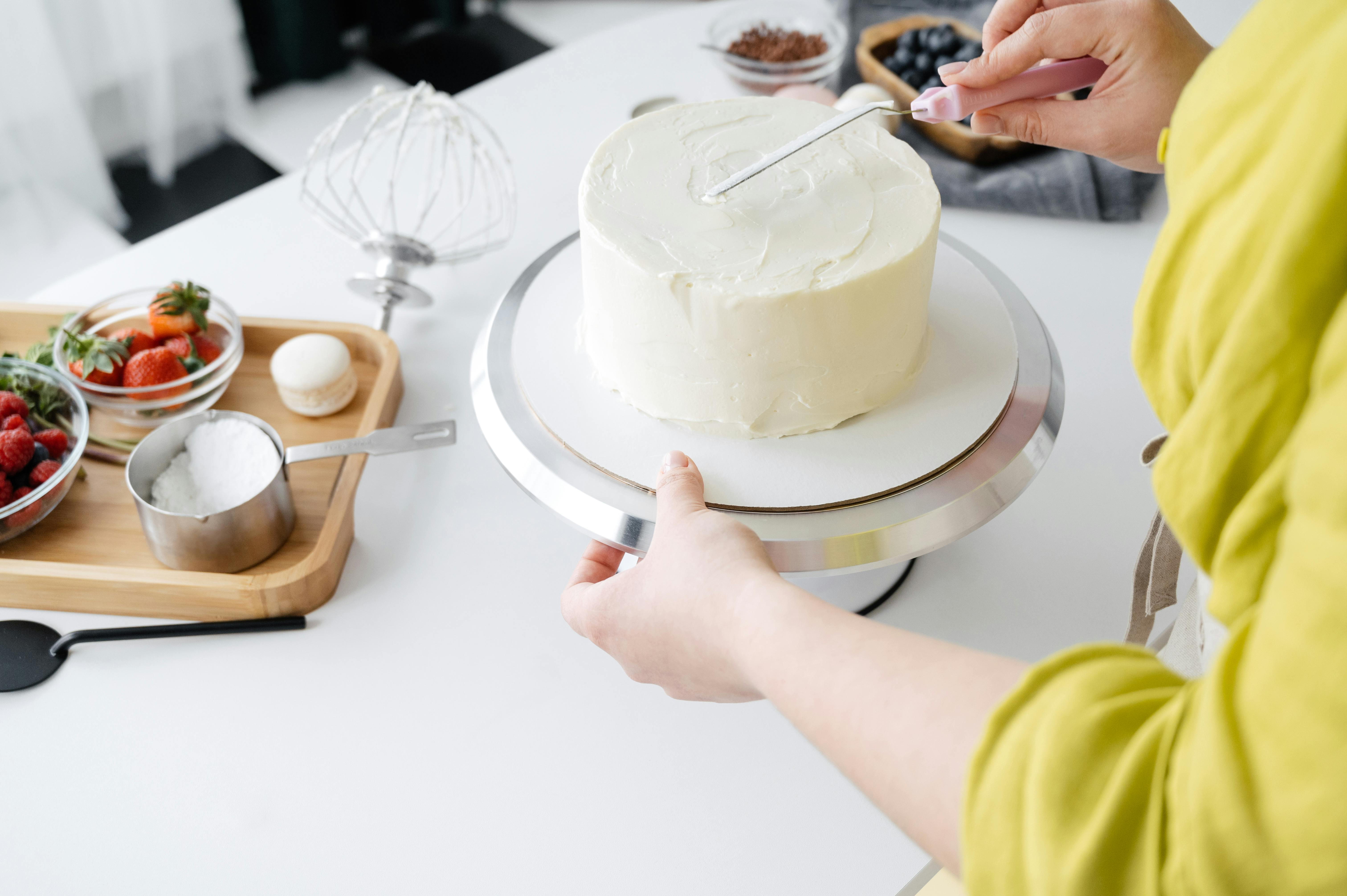 woman hands decorating biscuit cake with cream