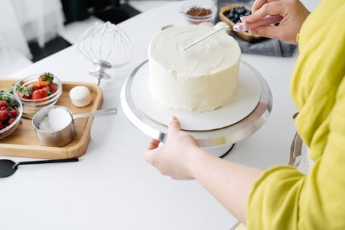 Free Woman hands decorating biscuit cake with cream Stock Photo