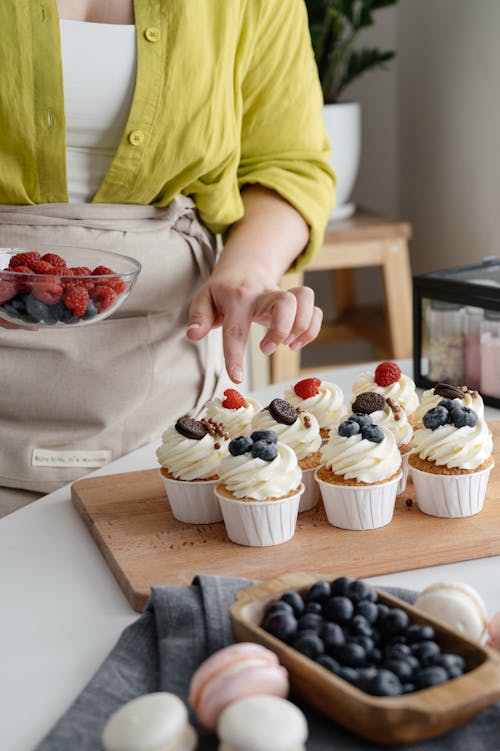 Female cook decorating cupcakes with berries