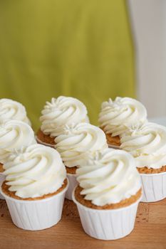 A tempting array of frosted cupcakes, captured close-up on a wooden table.