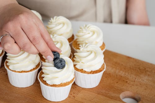 Close-Up Shot of a Person Putting Berries on a Cupcake