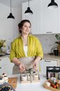 Woman tying bow on transparent box with cupcakes