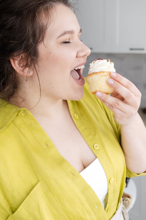 Woman eating cupcake with cream