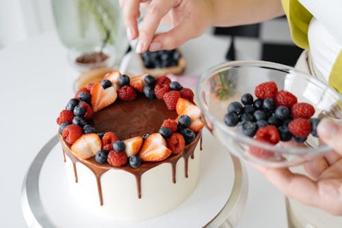 Free Female confectioner decorating homemade cake with berries Stock Photo