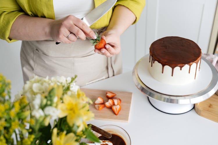 Woman Cutting Strawberry For Decoration Of Cake