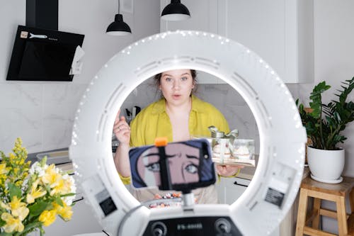 Young woman recording new vlog on smartphone in kitchen