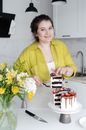 Happy housewife serving delicious cake in kitchen