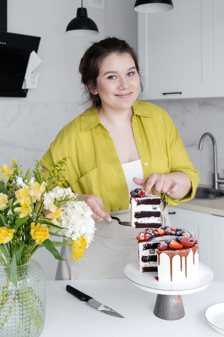 Happy Housewife Serving Delicious Cake In Kitchen