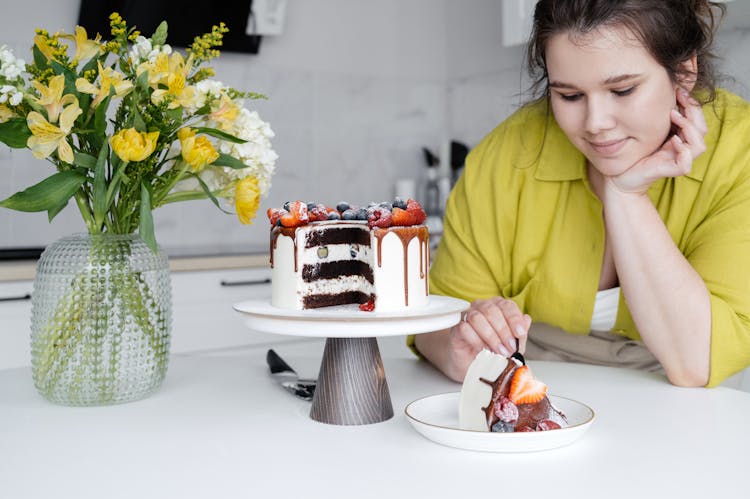 Positive Young Woman Eating Yummy Cake In Kitchen