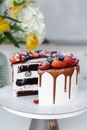 Yummy freshly baked cake with white cream decorated with assorted berries served on tray in light kitchen