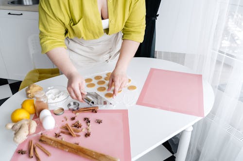 From above of crop unrecognizable female cook standing near table and cooking delicious homemade gingerbread cookies