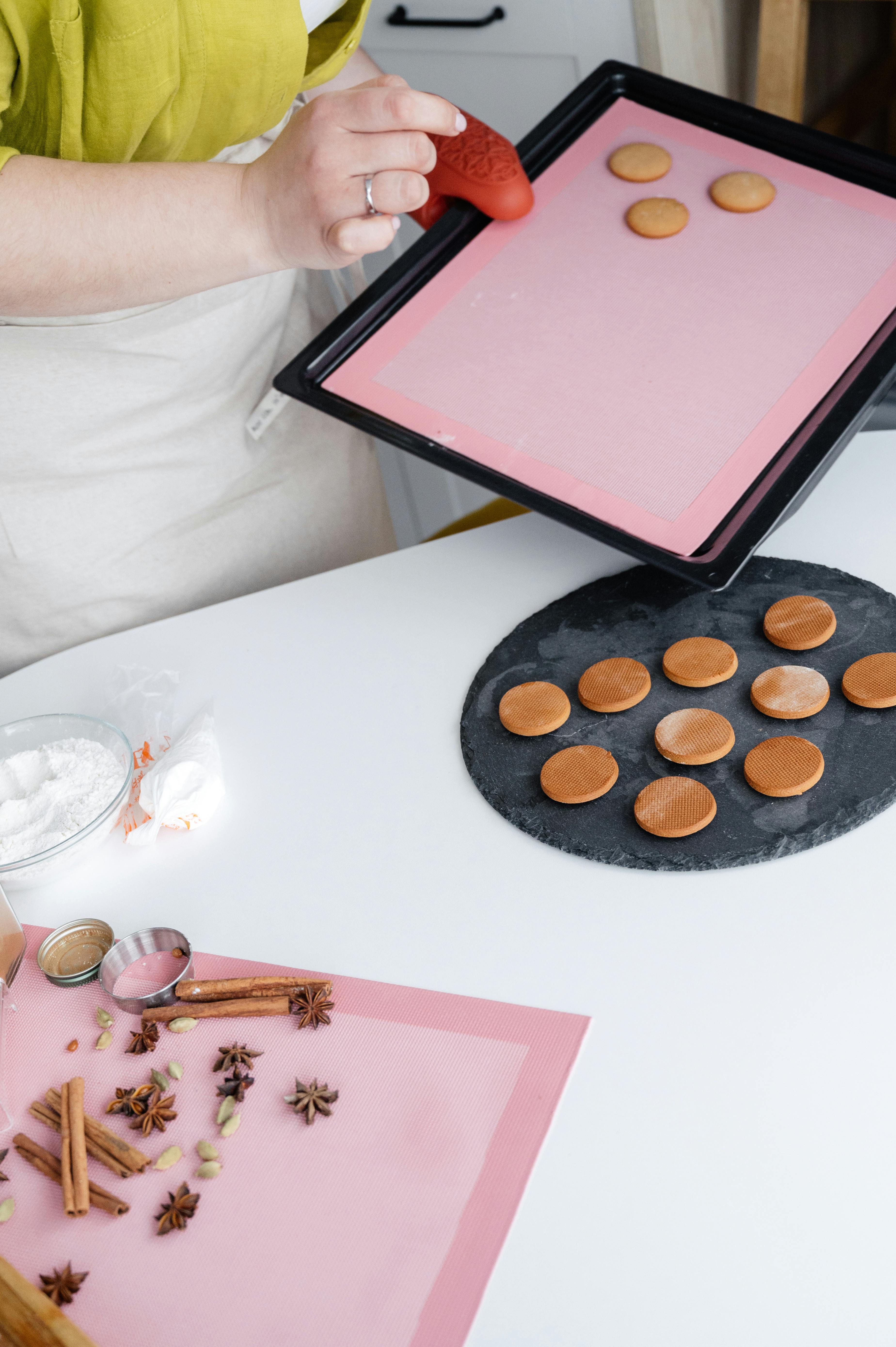 crop woman removing cookies from baking pan