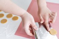 Crop woman placing unbaked cookies on baking mat