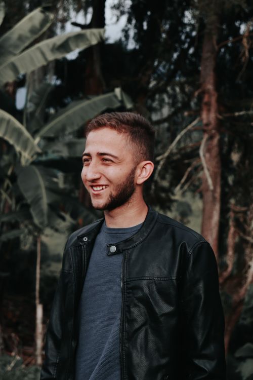 Free A smiling man in a black leather jacket enjoying the outdoors in a forest in Caldas, Colombia. Stock Photo