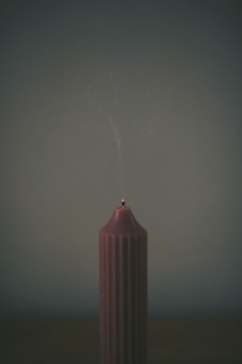 Free Elegant close-up of a single candle with smoke rising, creating a moody atmosphere. Stock Photo