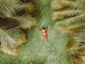 Woman lying on green grass among palms at resort