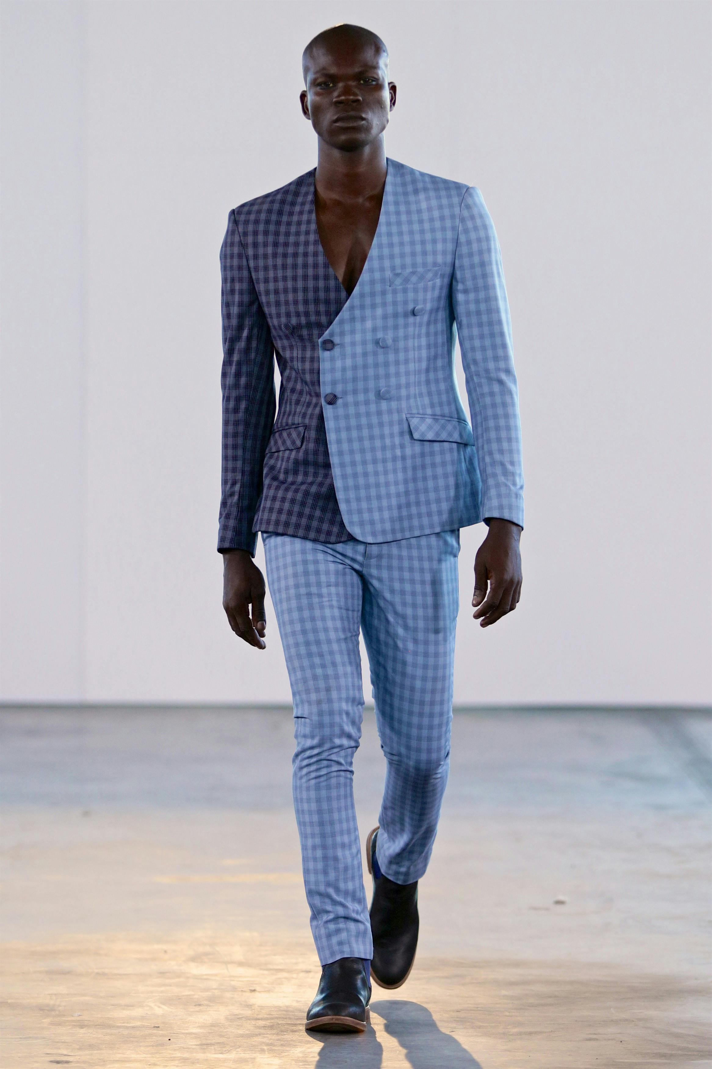 Male model in a blue check suit walking a runway