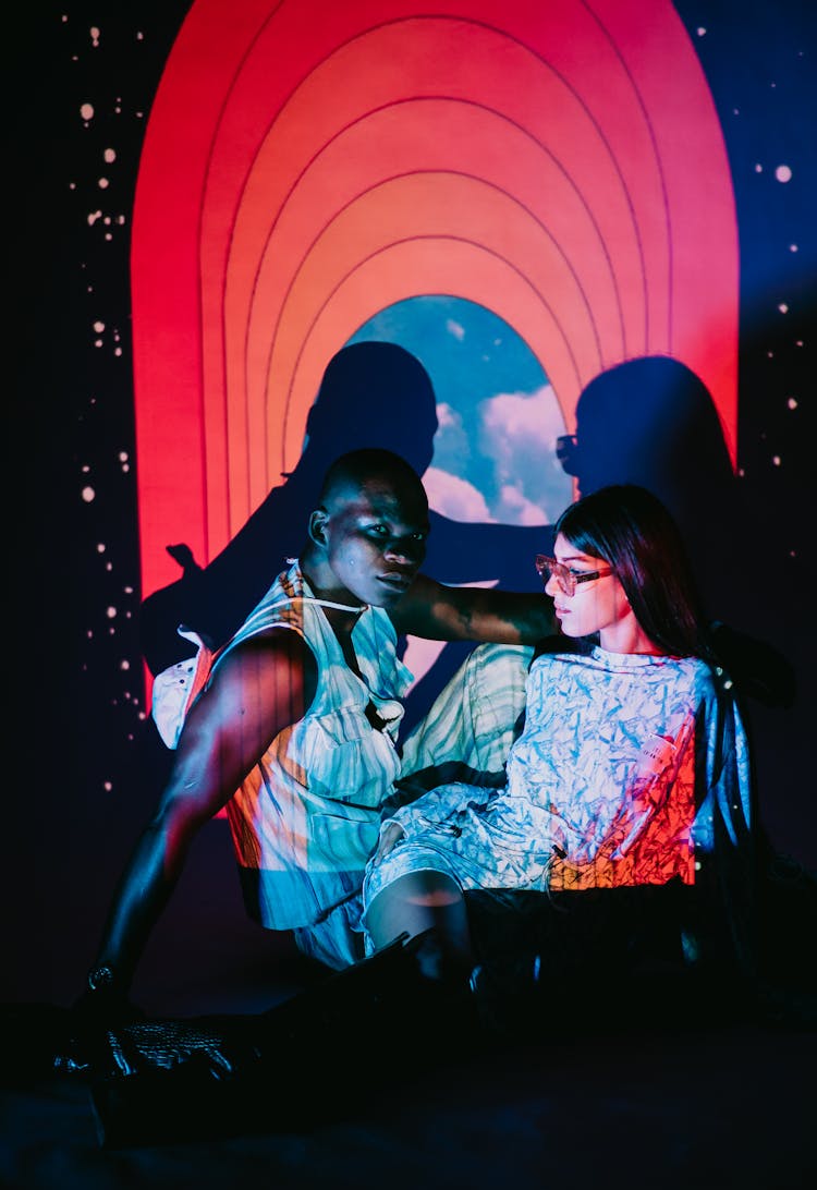 Confident Diverse Couple Sitting In Projection Light