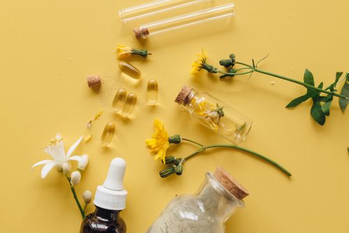 Free Top view of herbal supplements, flowers, and essential oils for natural wellness on yellow background. Stock Photo